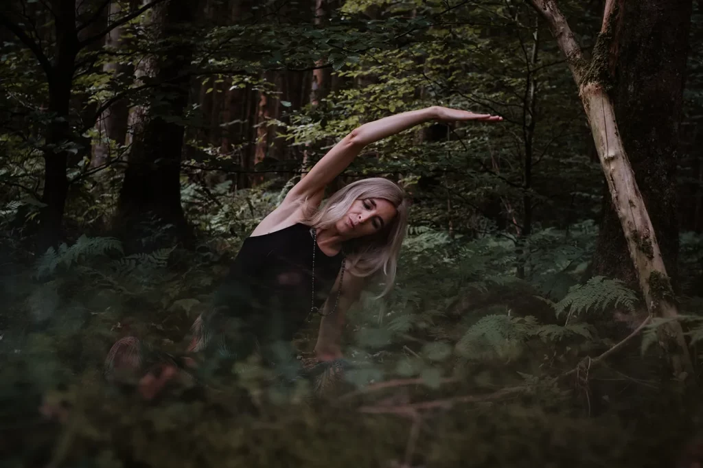 Maja Keppler in einer seitlichen Yogapose, umgeben von einem ruhigen Wald