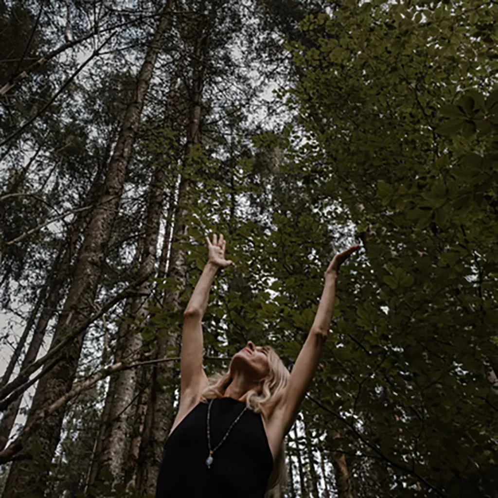 Maja Keppler streckt im Wald ihre Arme nach oben.